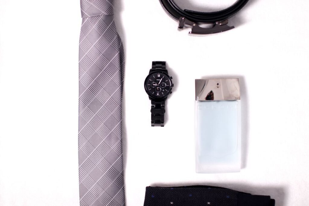 Flat lay of a tie, watch and leather accessories showing how to pick men's accessories